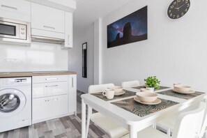 Eine moderne Küche mit Mikrowelle, Waschmaschine und Essbereich mit Tisch für vier Personen.