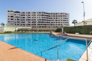 A swimming pool with a tiled deck, a building with multiple balconies in the background, and a sign that reads 'Los Molinos'. - Blue sky:  ocean view & 5 min to Jumbo (Playa del Ingles)