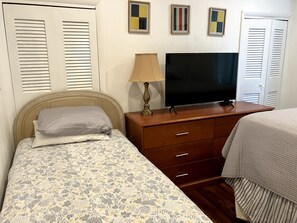 Ein Schlafzimmer mit einem Bett, einem Fernseher, einer Lampe und einer Kommode.