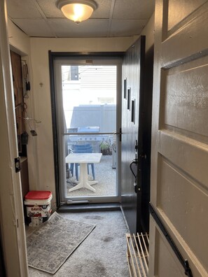 A doorway leading to an outdoor area with a table and chairs, a rug, and a storage box labeled 'DAVID' on the floor. - Spacious 3-bedroom condo with pool and laundry, steps from beach and boardwalk! (Wildwood)