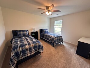 A bedroom with two beds, a ceiling fan, a nightstand, and a window. - Spacious Home Near UAB Medical West. Quiet Neighborhood, Easy Birmingham Access (Bessemer)