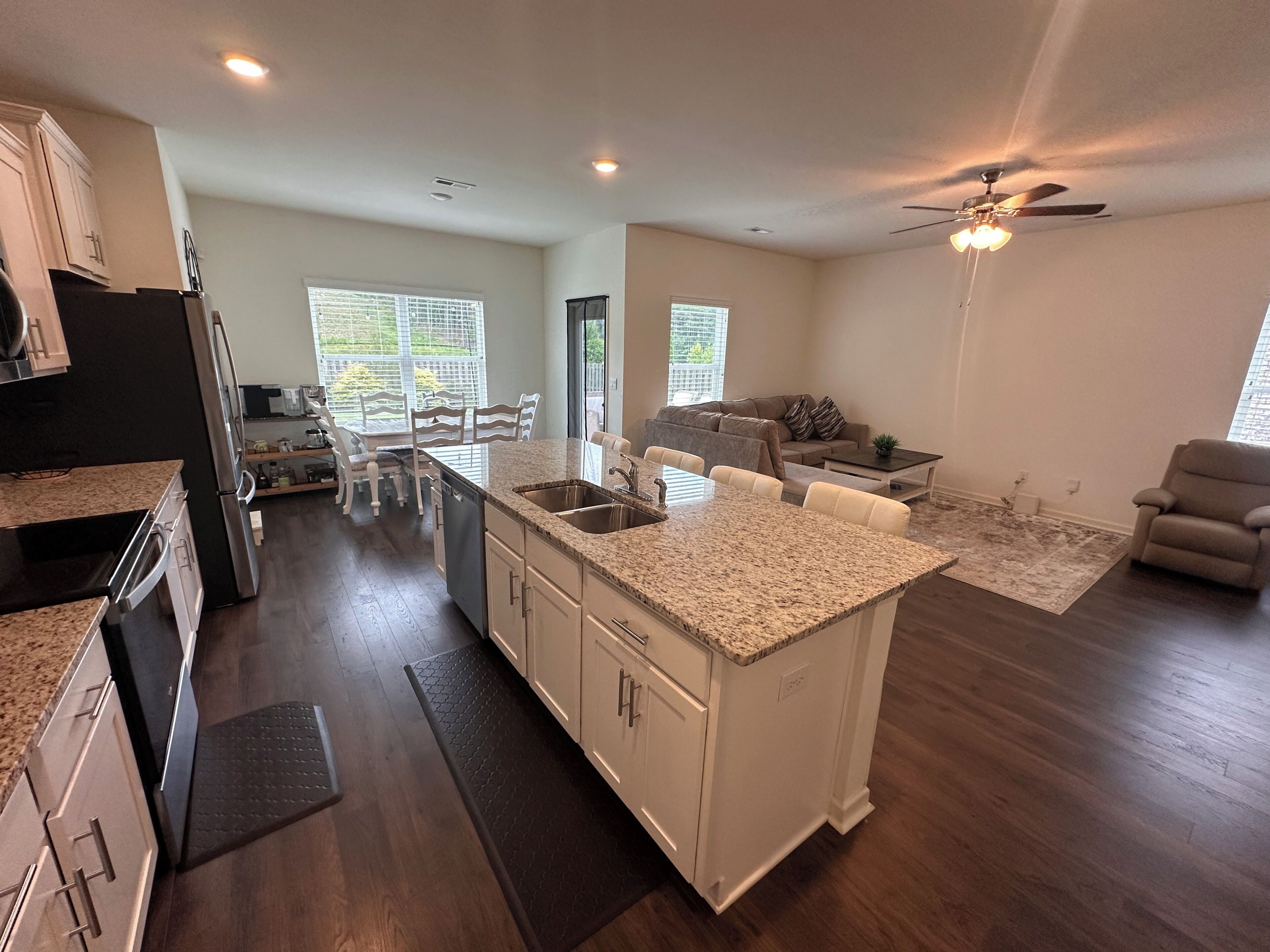 A modern kitchen with granite countertops, a built-in island, and a dining area with white chairs.