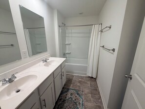 A bathroom with a double sink, a shower, and a mirror. - Spacious Home Near UAB Medical West. Quiet Neighborhood, Easy Birmingham Access (Bessemer)