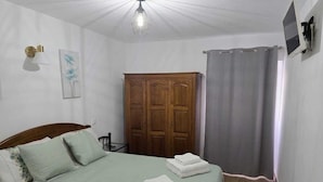 Ein Schlafzimmer mit einem Bett, einem Kleiderschrank, einer Duschvorhang und einem an der Wand befestigten Fernseher.