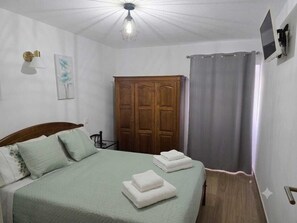 A bedroom with a bed, a wardrobe, a shower curtain, and a wall-mounted TV. - Casa Maria da Eira (gração)