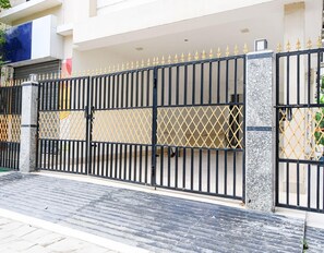 A gated entrance with a metal gate, a paved driveway, and a building in the background. - Classic Moubani Residency (Barasat)