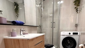 Un baño moderno con lavabo, inodoro, ducha y lavadora.
