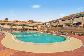 A swimming pool with lounge chairs and a tiled deck, surrounded by multi-story buildings with balconies. - Spacious and Bright 'Mareverde' Apartment with Sea Views, Pool, and WiFi (Adeje)