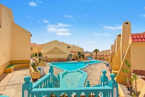 A resort pool area with a central swimming pool, sun loungers, and a staircase leading to a higher level. - Spacious and Bright 'Mareverde' Apartment with Sea Views, Pool, and WiFi (Adeje)