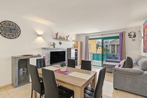 A modern living room with a dining area, a fireplace, and a balcony with a view. - Spacious and Bright 'Mareverde' Apartment with Sea Views, Pool, and WiFi (Adeje)