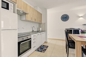 Eine moderne Küche mit weißen Schränken, Edelstahlgeräten und einer Holzausziehtafel.