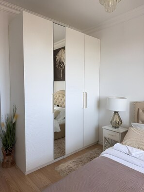 A bedroom with a large wardrobe, a bed with a headboard, a nightstand with a lamp, and a decorative mirror. - LUX Apartment Amazing View – piękny widok, blisko centrum Wrocławia. (Wrocław)