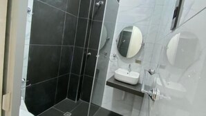 Casa de banho moderna com cabine de duche em vidro, lavatório branco e sanita.