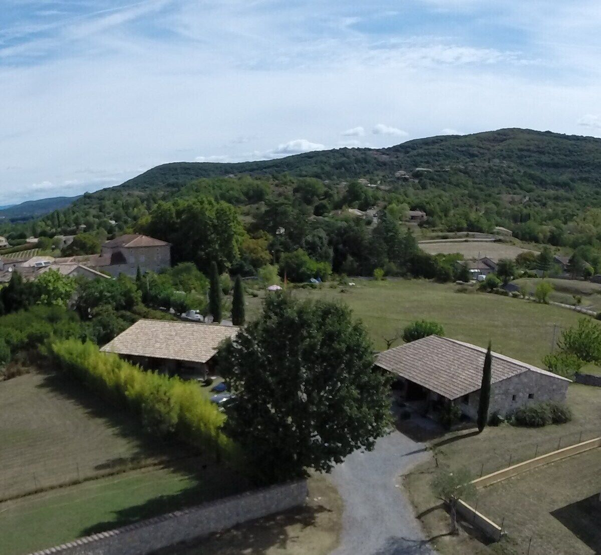 A rural landscape with houses, a road, and a hill in the background.