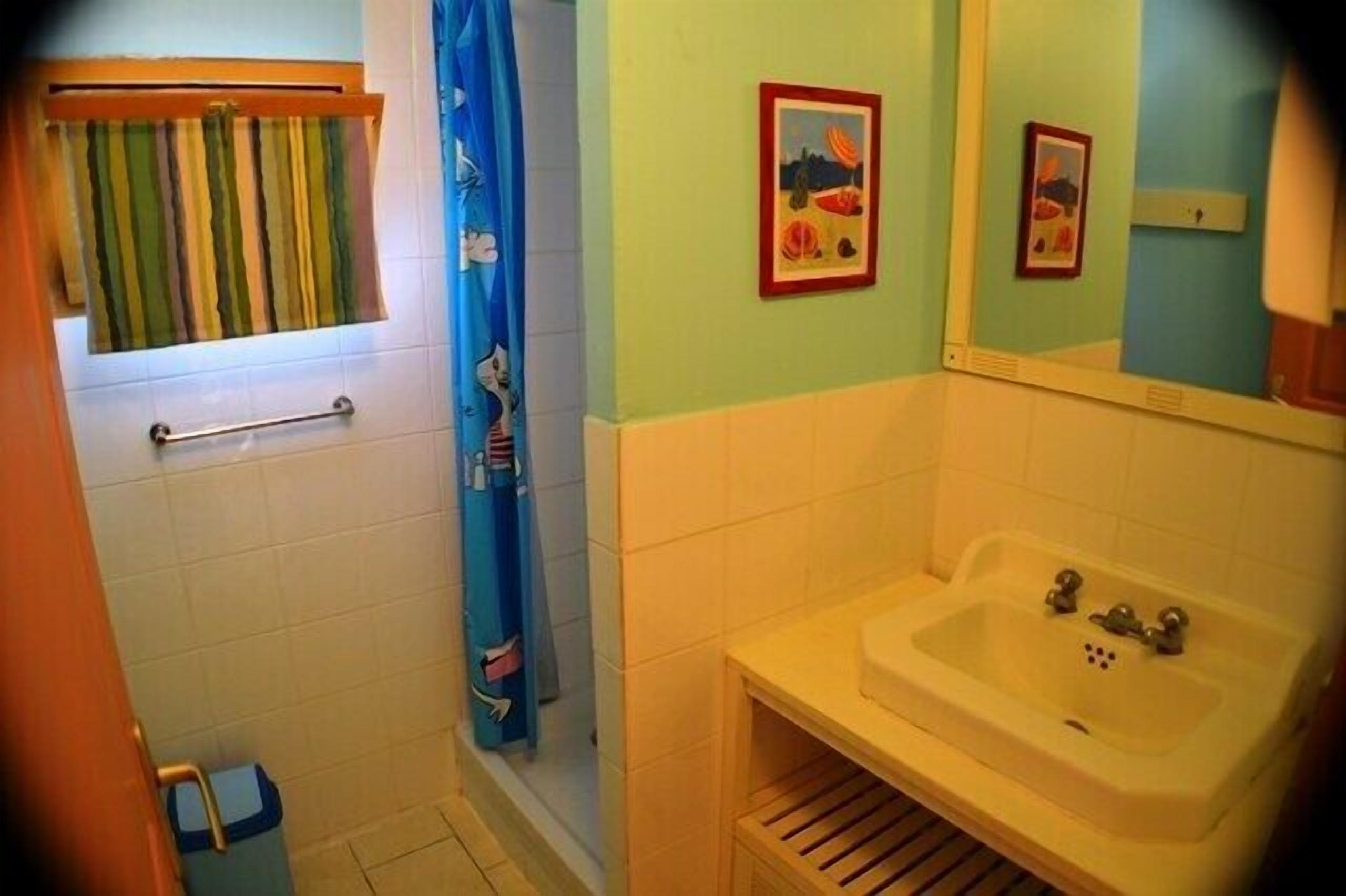 Un baño con ducha, lavamanos y ventana con toallero.