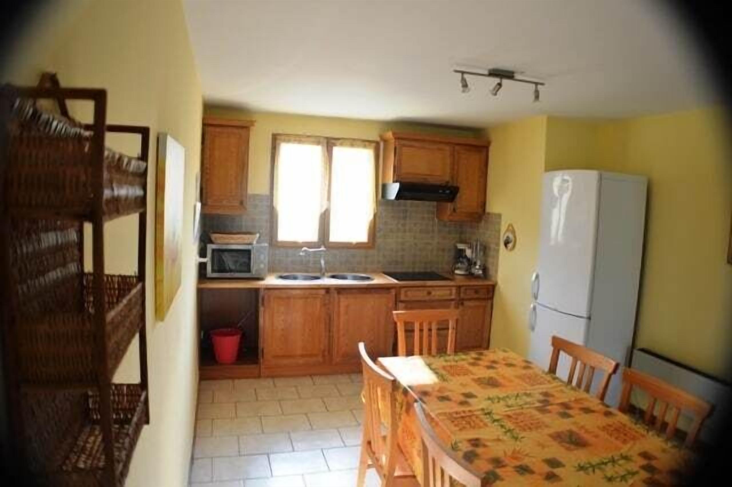 A kitchen with wooden cabinets, a microwave, a sink, and a dining table with chairs.