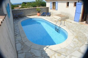 A swimming pool with a stone border, a lounge area with chairs, and a view of the surrounding landscape. - "Océane" Villa, with private pool, sleeps 10 (Grospierres)