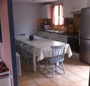 A compact kitchen with a dining table, chairs, a refrigerator, and a microwave. - "Océane" Villa, with private pool, sleeps 10 (Grospierres)