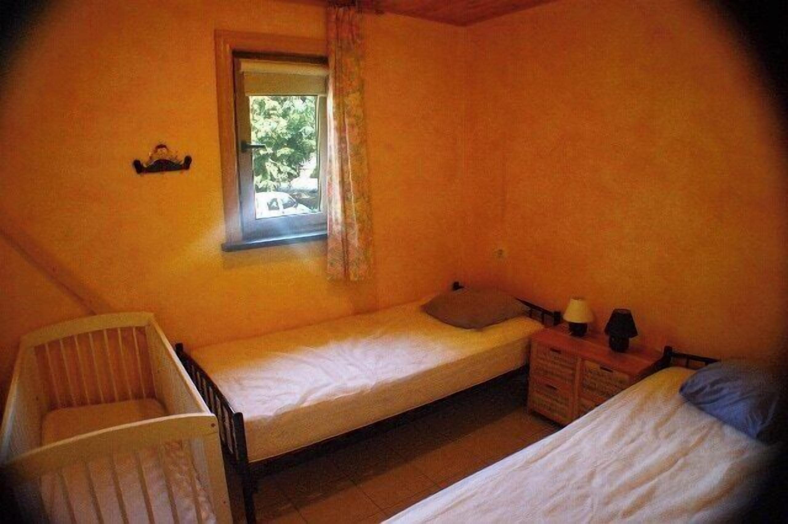 A small, single-room accommodation with a bunk bed, a crib, and a window.