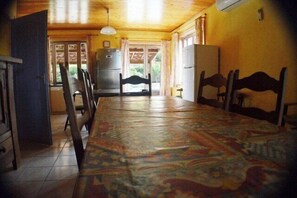 A room with a large bed, a wooden ceiling, a refrigerator, and a window with curtains. - "Au Grand Bonheur" Villa, with a pool, sleeps 15 (Grospierres)