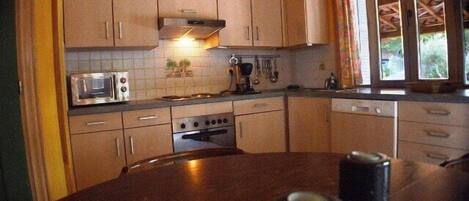 Una cocina con estufa, microondas y armarios.
