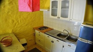 Une cuisine de taille réduite avec des meubles blancs, un évier et un réfrigérateur bleu.