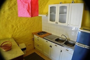 Une cuisine de taille réduite avec des meubles blancs, un évier et un réfrigérateur bleu.