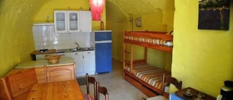 Habitación compacta con literas, una kitchenette pequeña y una zona de comedor.