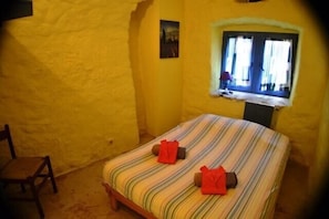 Een kamer met een bed, een raam en een stoel.