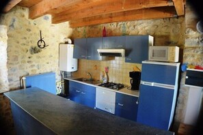 Een keuken met blauwe kastjes, een magnetron en een fornuis.