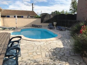 A swimming pool with a stone patio, lounge chairs, and a wooden table. - "Margaux" Villa, pool, patio, private BBQ, sleeps 8 (Grospierres)