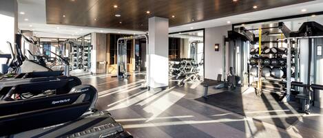 Une salle de sport moderne équipée de tapis de course, d’appareils de musculation et de poids libres.