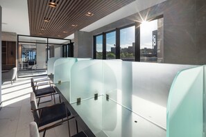 A modern office space with glass partitions, a wooden ceiling, and a view of the city through large windows.