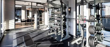 Un gimnàs modern amb diversos equips per a aixecar peses, incloent una barra per a squats i kettlebells.