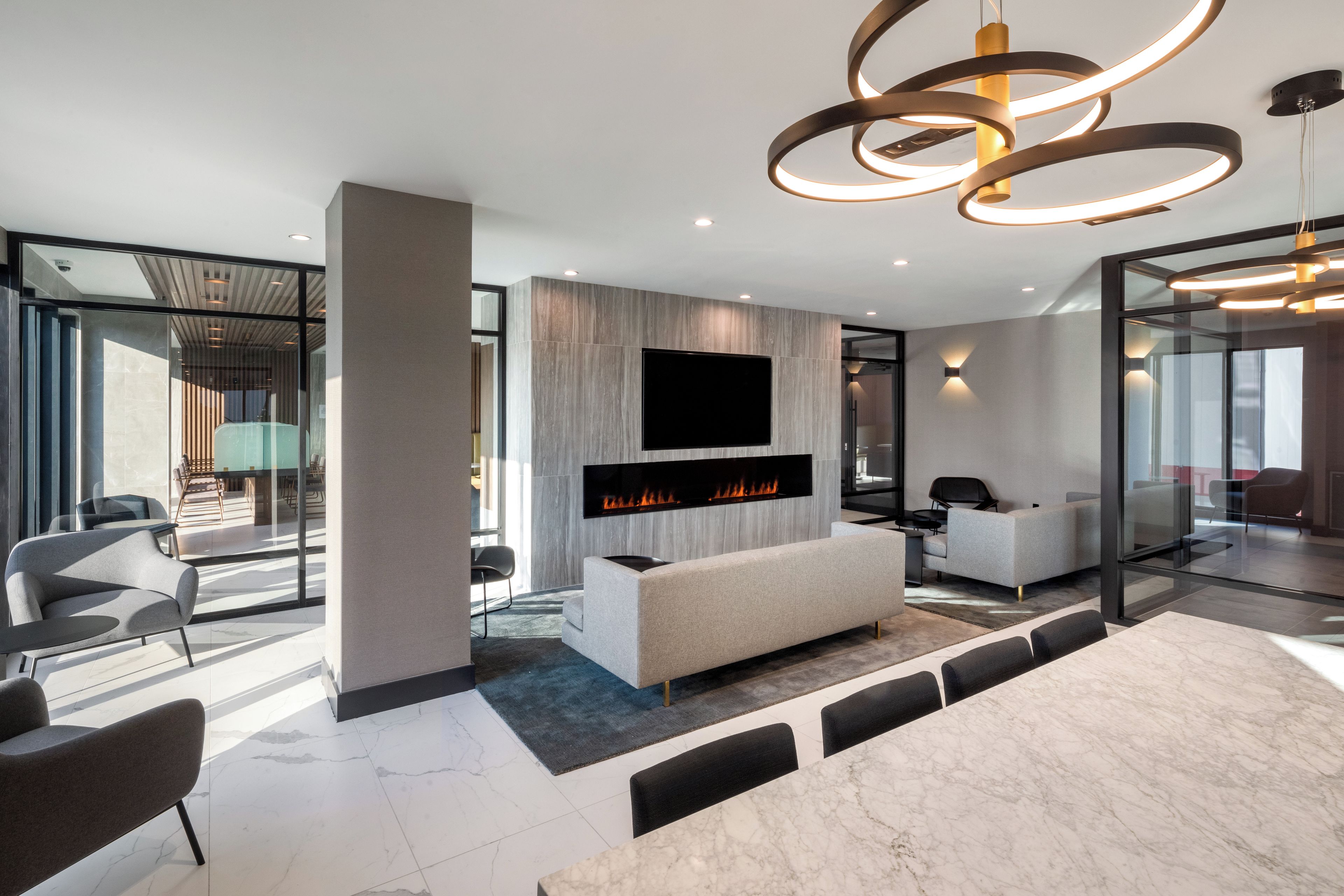 A modern interior with a fireplace, seating area, and a large flat-screen TV mounted on the wall.