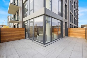 A modern building with large glass windows, a wooden fence, and a clear view of the cityscape.