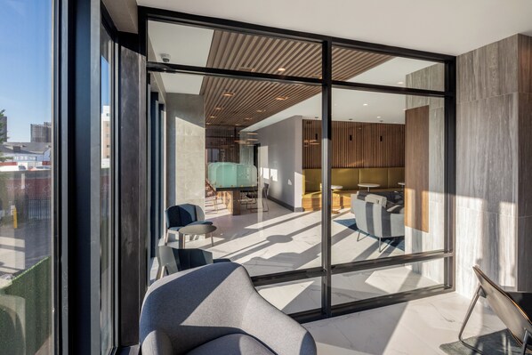 A modern interior with a glass wall, seating area, and a view of the city.