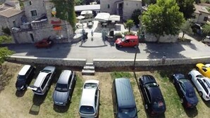 Un parcheggio con diverse auto, un edificio con un cartello e un muro in pietra.