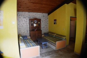 A room with a stone wall, wooden ceiling, a sofa set, a small table, and a cabinet.