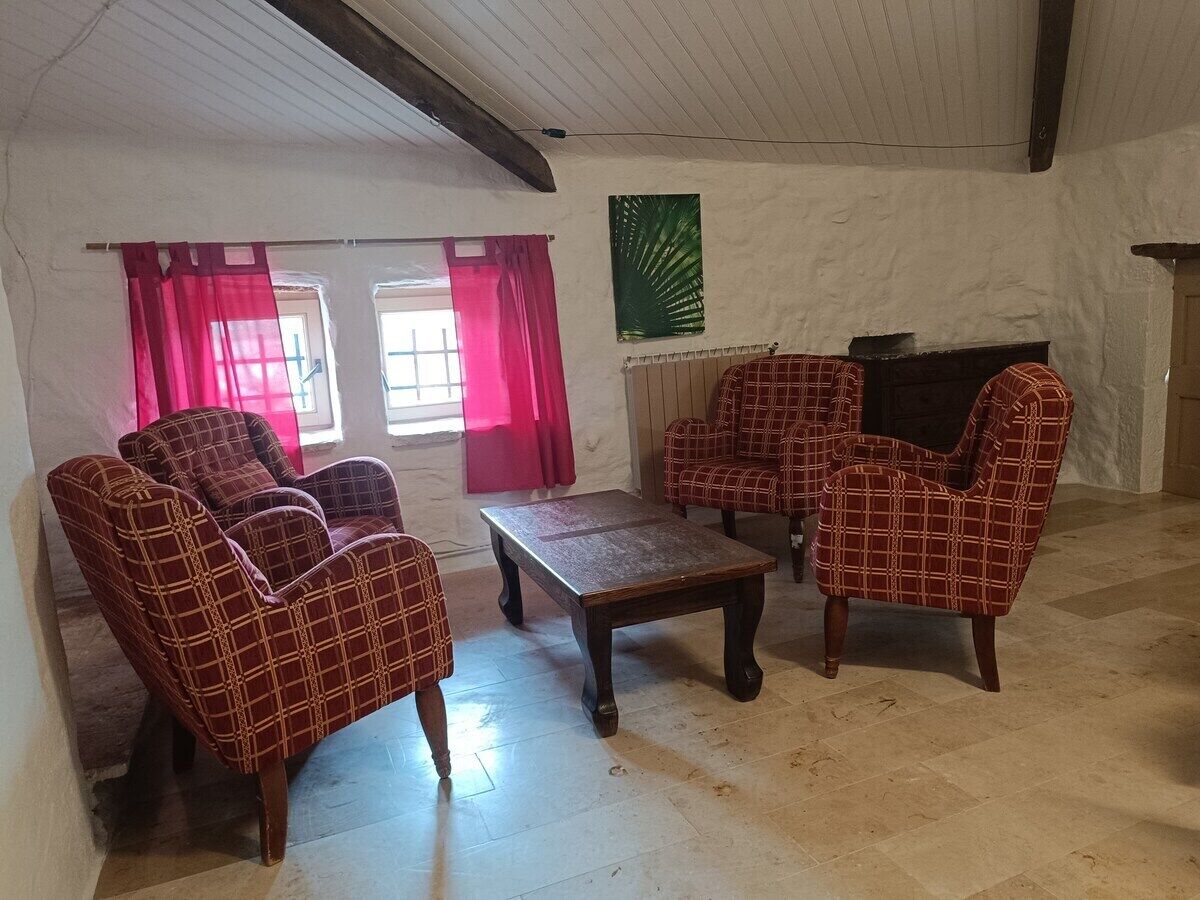 A room with a fireplace, a coffee table, and four armchairs.