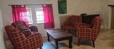 Quarto com lareira, mesa de centro e quatro poltronas.