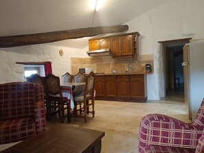Ein Essbereich mit Tisch und Stühlen, Holzschränken sowie eine Küchenzeile mit Herd und Spüle.