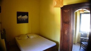 A single bed in a room with a yellow wall, a framed picture, and a wooden door. - Vacation Rental #8, Sleeps 6, Domaine de Ribière (Grospierres)