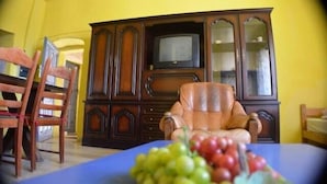 A dining area with a table set for two, a wooden cabinet with a television, and a yellow wall. - Vacation Rental #8, Sleeps 6, Domaine de Ribière (Grospierres)