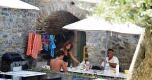 An outdoor dining area with stone walls, tables, and umbrellas. - Cottage #19, with a patio and pool access (Grospierres)