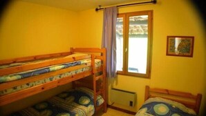 A room with bunk beds, a window with curtains, and a radiator.