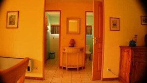 A hallway with a door leading to a bathroom, a small table with a lamp, and a cabinet.