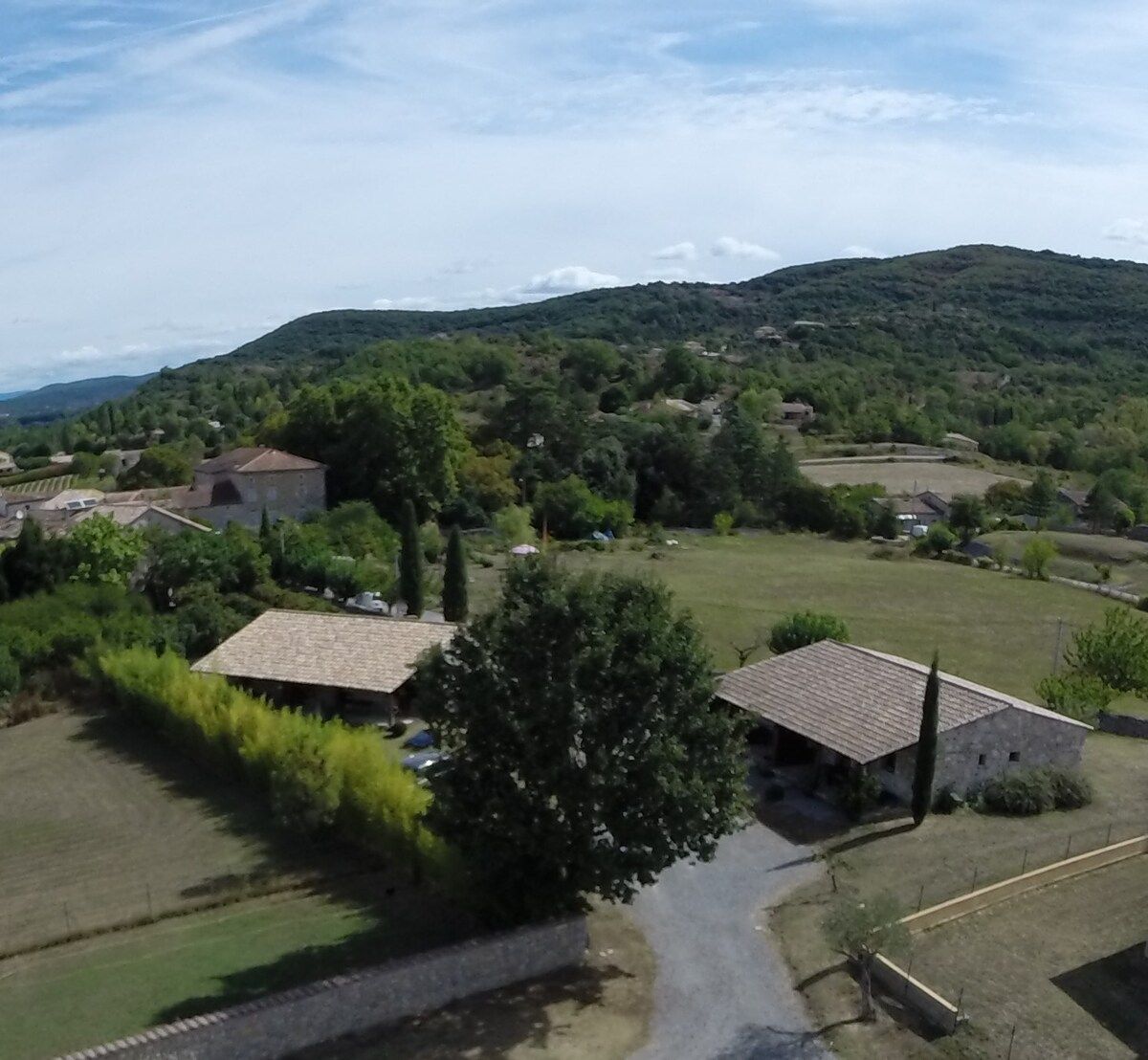 A rural landscape with houses, a road, and a hill in the background.