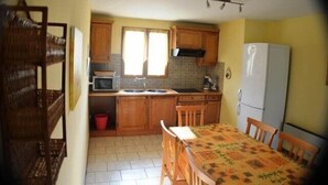 A kitchen with wooden cabinets, a microwave, a sink, and a dining table with chairs.