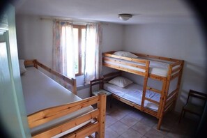 A room with two bunk beds, a window with curtains, and a chair. - Villa de La Treille B, pool, patio, BBQ, sleeps 8 (Grospierres)